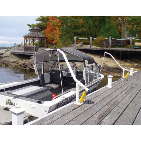 A white boat with a cover is being held in place by mooring whips. 